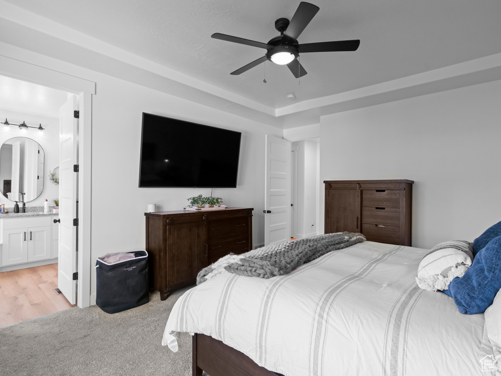 Bedroom featuring ensuite bathroom, a ceiling fan, and light carpet