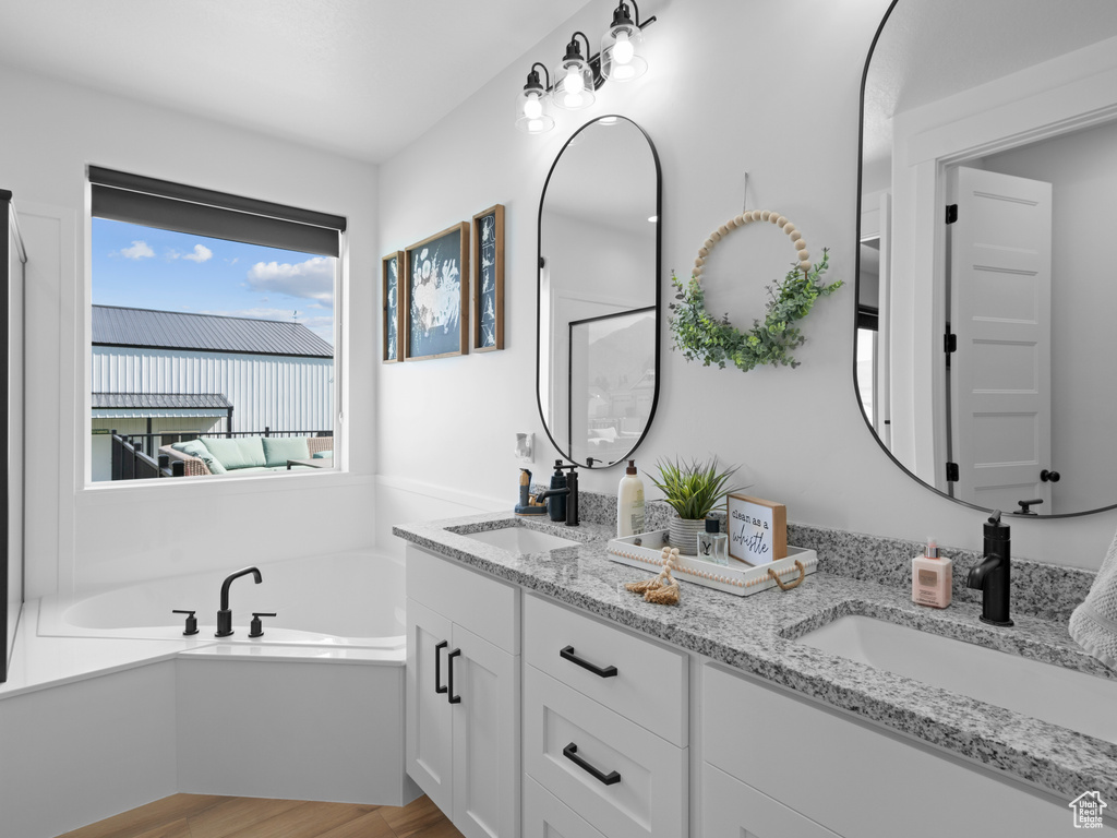 Bathroom with wood finished floors, double vanity, and a bath