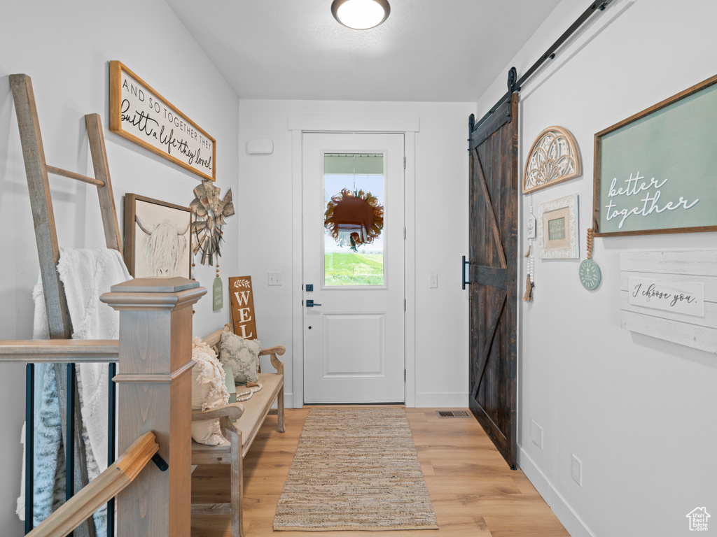 Foyer with a barn door, wood finished floors, and baseboards