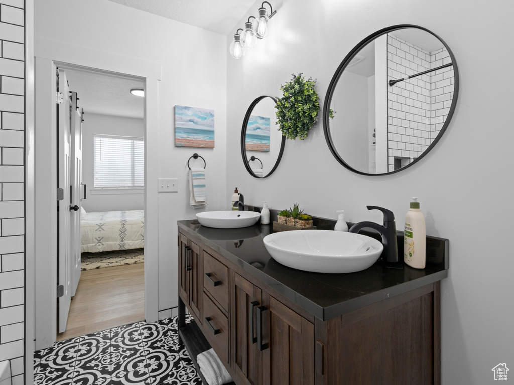 Ensuite bathroom featuring double vanity and wood finished floors