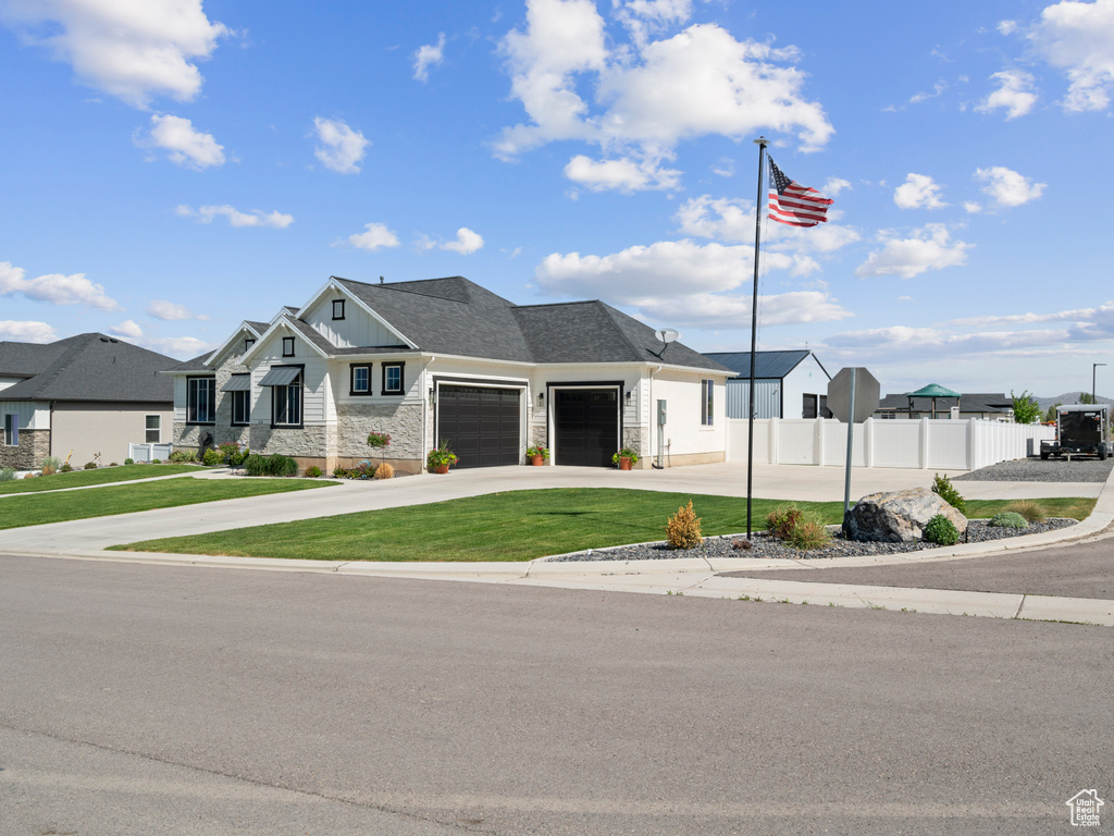 View of front of home featuring an attached garage, board and batten siding, driveway, a residential view, and stone siding
