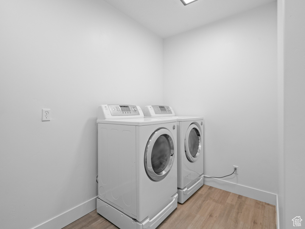 Washroom with separate washer and dryer, light wood-style flooring, and baseboards