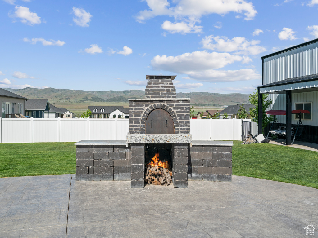 View of patio / terrace featuring an outdoor brick fireplace and a mountain view