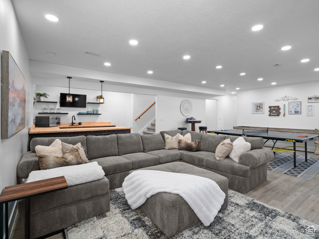 Living area featuring recessed lighting, wood finished floors, wet bar, and stairway