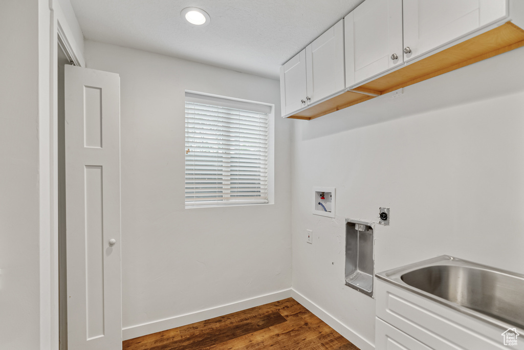 Laundry room featuring dark wood-style flooring, cabinet space, washer hookup, electric dryer hookup, and baseboards