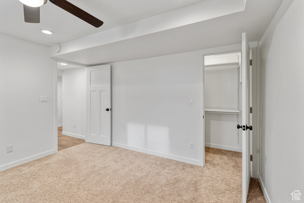 Unfurnished bedroom featuring recessed lighting, a ceiling fan, a walk in closet, carpet, and baseboards