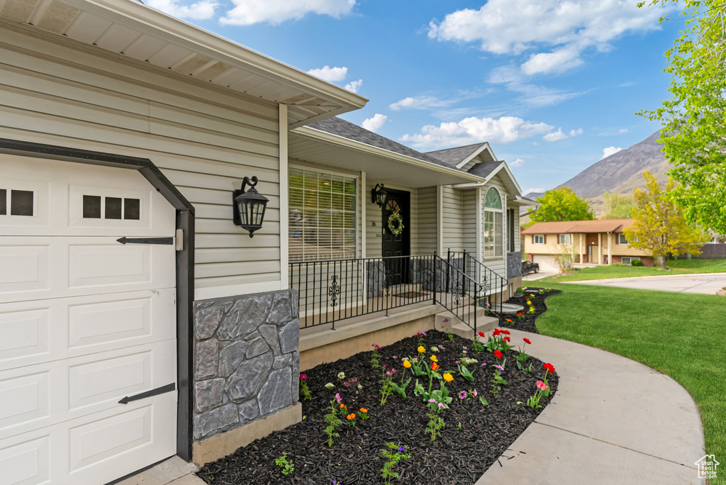 Entrance to property with a lawn, roof with shingles, a mountain view, and stone siding