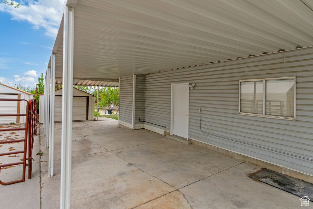View of patio with an attached carport, a shed, and an outbuilding