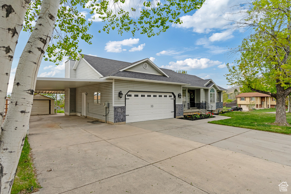 View of front of property with driveway, a carport, roof with shingles, a front yard, and a garage