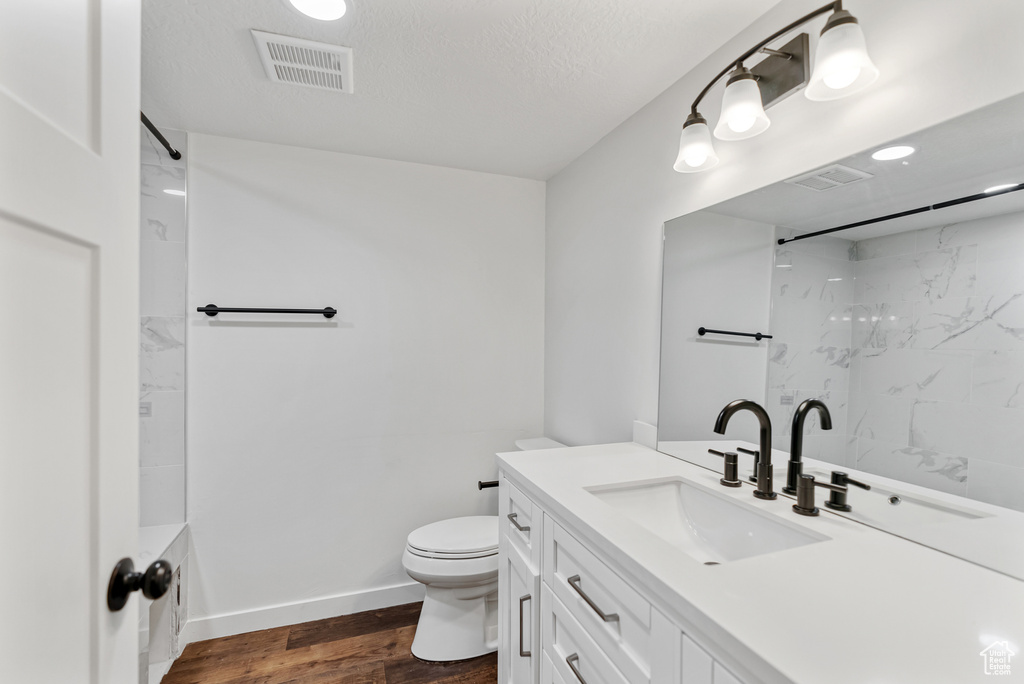 Bathroom featuring visible vents, baseboards, toilet, wood finished floors, and vanity
