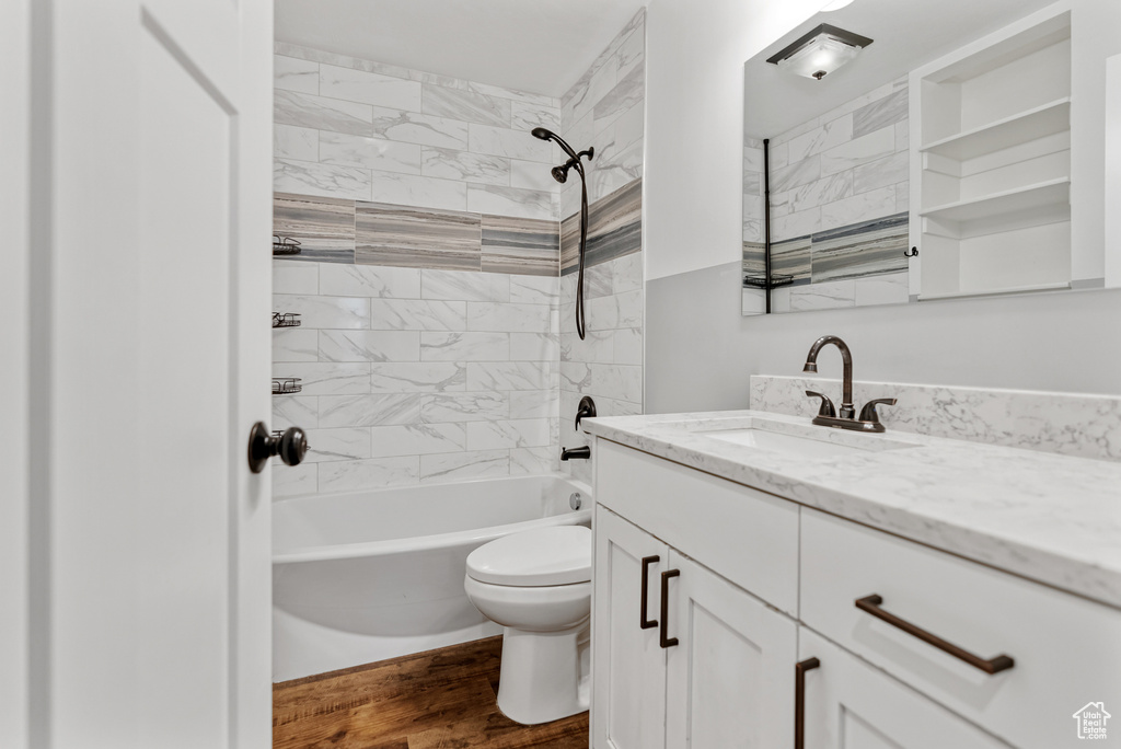 Full bathroom featuring wood finished floors, toilet, tub / shower combination, and vanity