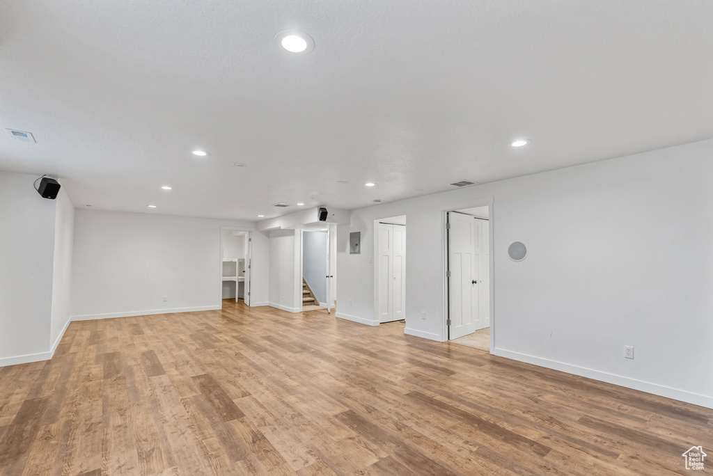 Unfurnished living room with recessed lighting, visible vents, stairway, and light wood-type flooring