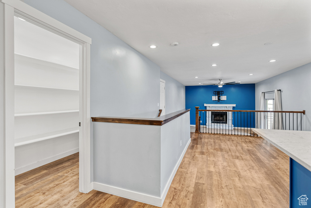 Hallway with baseboards, recessed lighting, an upstairs landing, and light wood finished floors