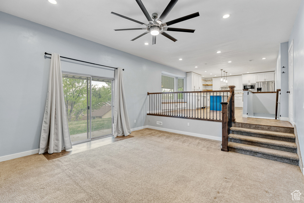 Unfurnished living room with recessed lighting, a ceiling fan, light carpet, and baseboards
