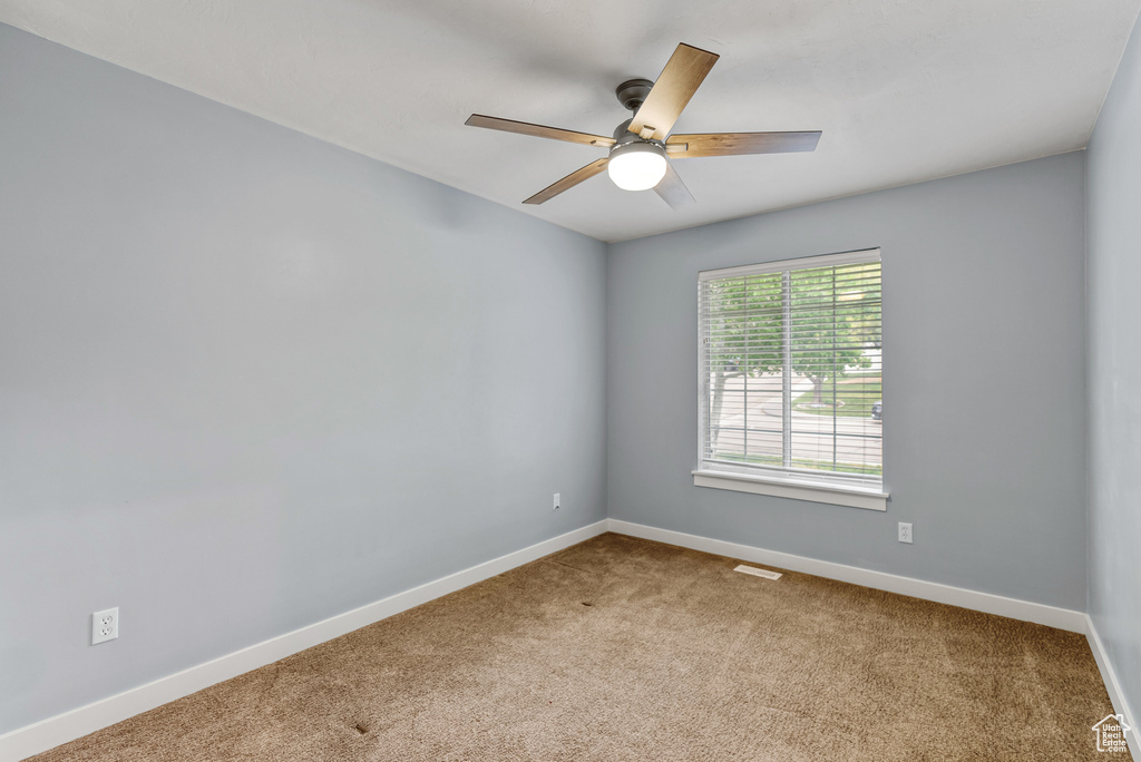 Unfurnished room featuring baseboards, visible vents, a ceiling fan, and carpet floors