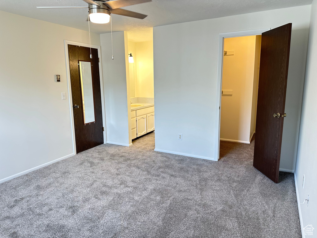 Unfurnished bedroom featuring carpet flooring, baseboards, ensuite bathroom, a sink, and ceiling fan