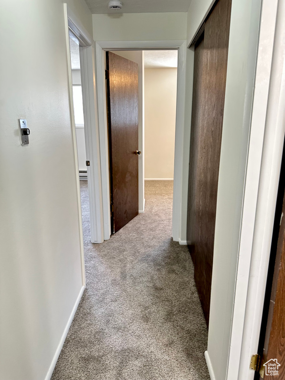 Corridor featuring carpet flooring and baseboards