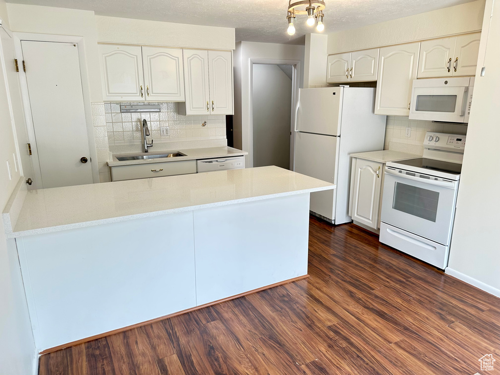 Kitchen featuring white appliances, a sink, decorative backsplash, white cabinetry, and dark wood finished floors
