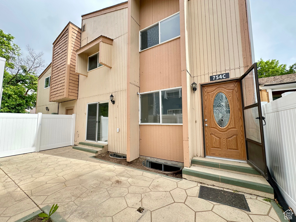 Property entrance featuring fence and a patio area