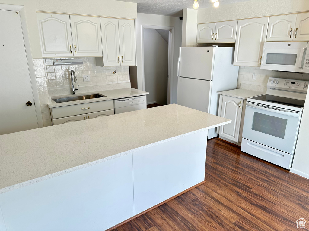 Kitchen featuring white appliances, a sink, decorative backsplash, and white cabinets