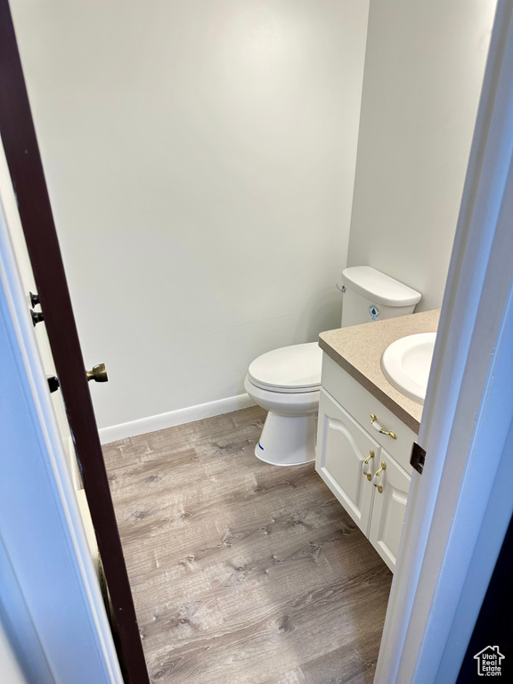 Bathroom with toilet, vanity, and wood finished floors