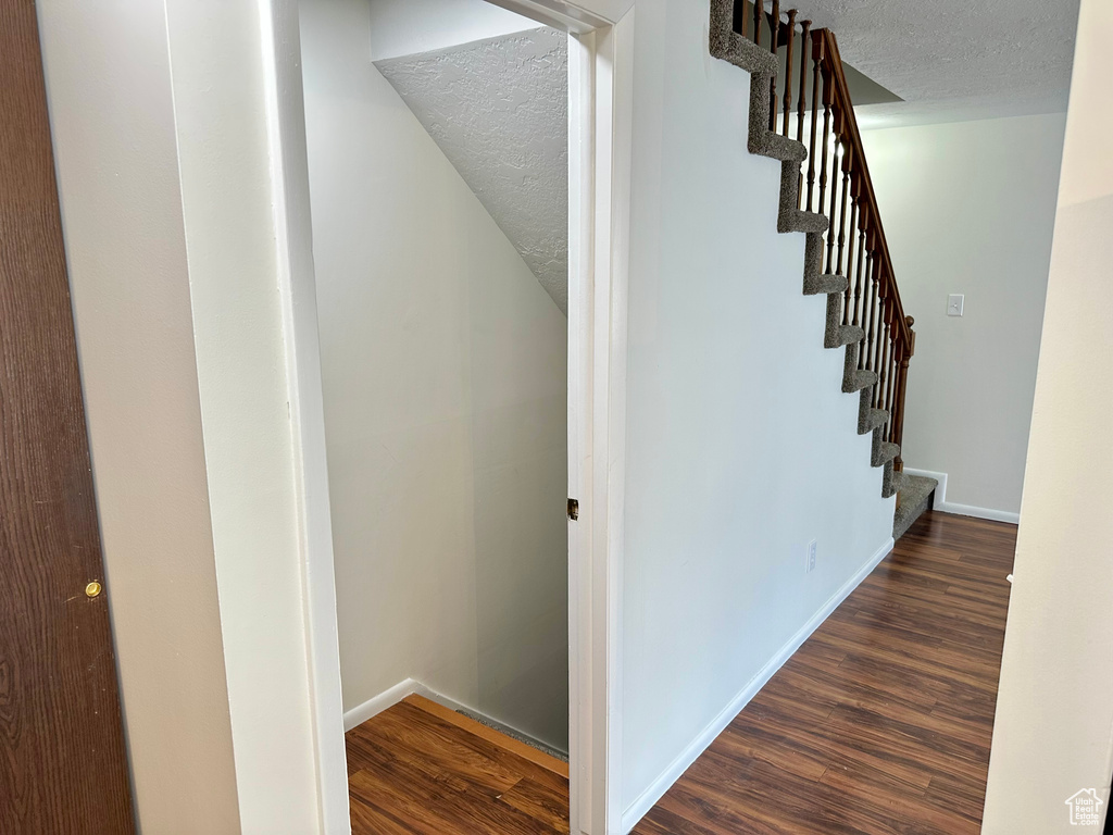 Stairs featuring a textured ceiling, wood finished floors, and baseboards