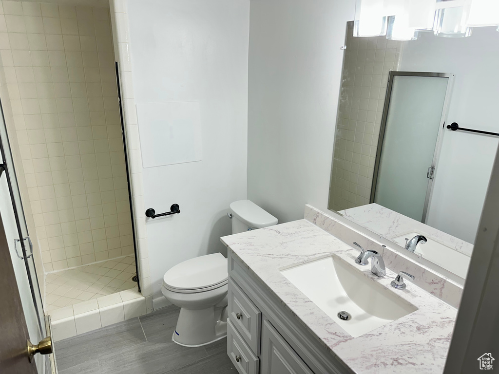 Bathroom with toilet, a stall shower, wood finished floors, and vanity