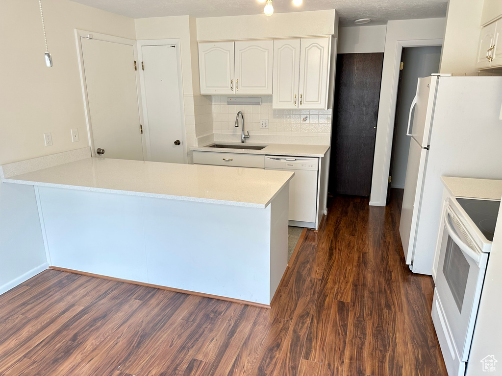 Kitchen featuring a sink, white appliances, a peninsula, and white cabinets