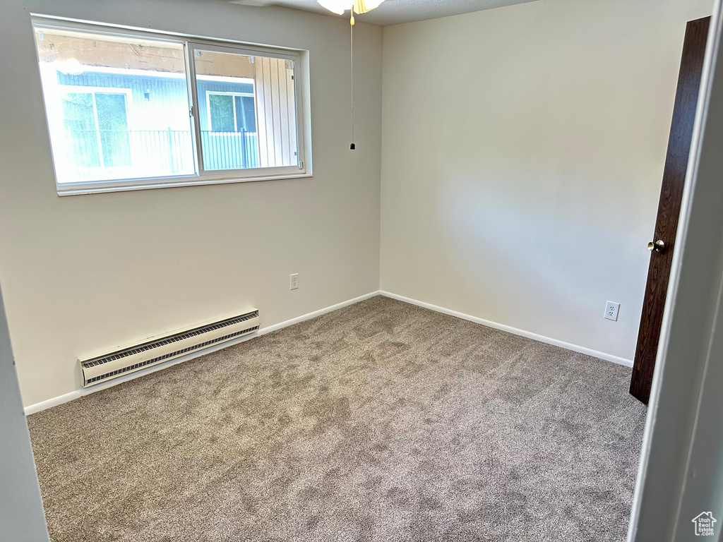 Spare room featuring a baseboard radiator, carpet, baseboards, and a ceiling fan
