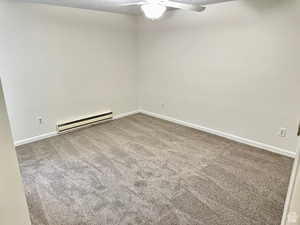 Carpeted empty room featuring a baseboard radiator, ceiling fan, and baseboards