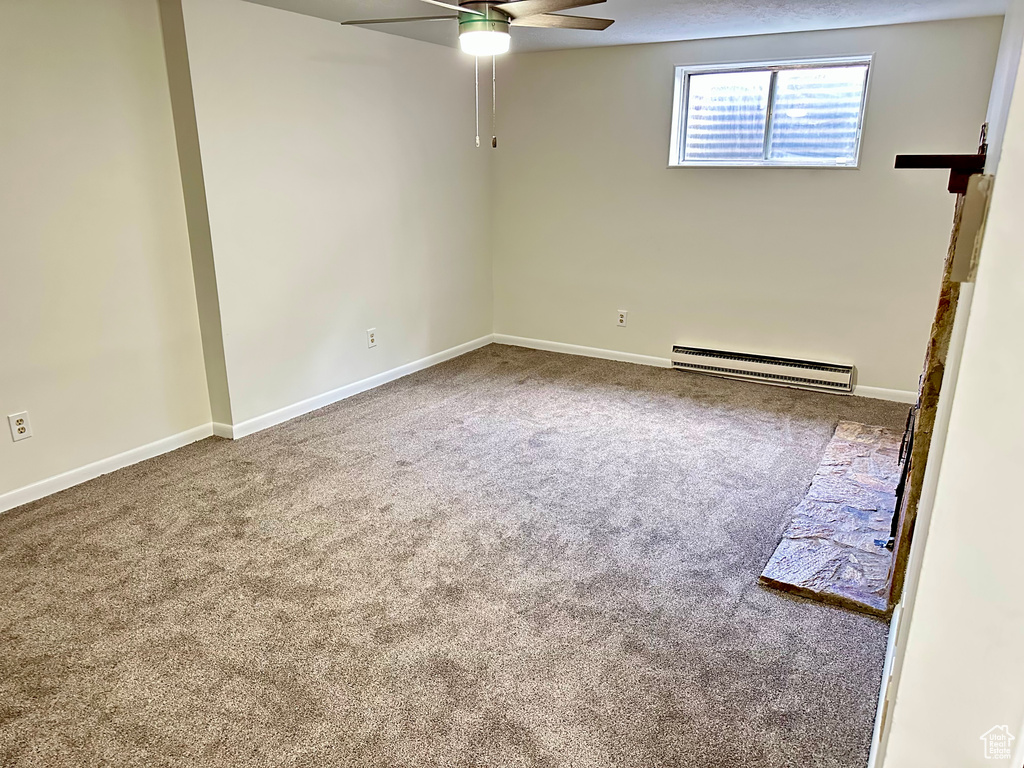 Carpeted empty room featuring a baseboard radiator, a ceiling fan, and baseboards