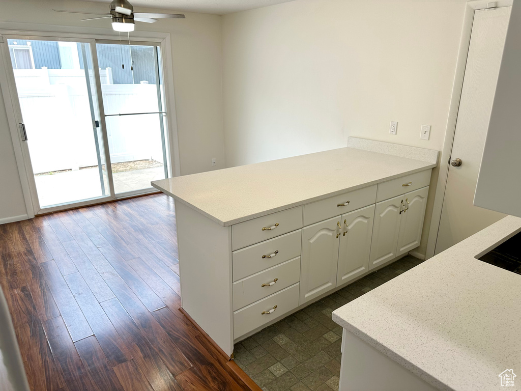 Kitchen featuring ceiling fan, a peninsula, dark wood finished floors, white cabinetry, and light countertops