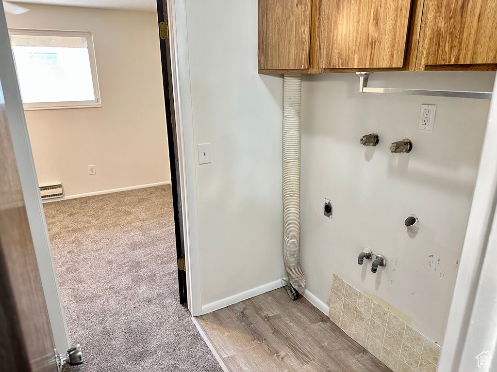 Laundry area featuring electric dryer hookup, cabinet space, light colored carpet, light wood-style flooring, and gas dryer hookup