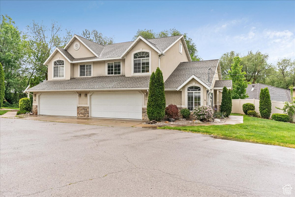 View of front of property featuring stone siding, stucco siding, a garage, and driveway