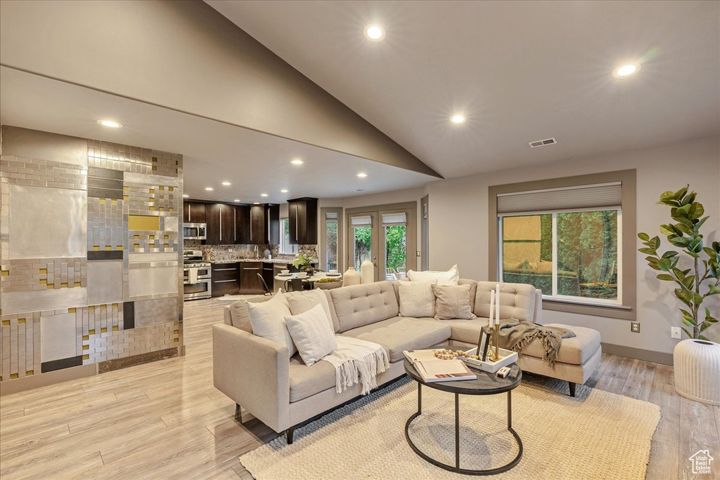 Living room with recessed lighting, light wood-style floors, and lofted ceiling