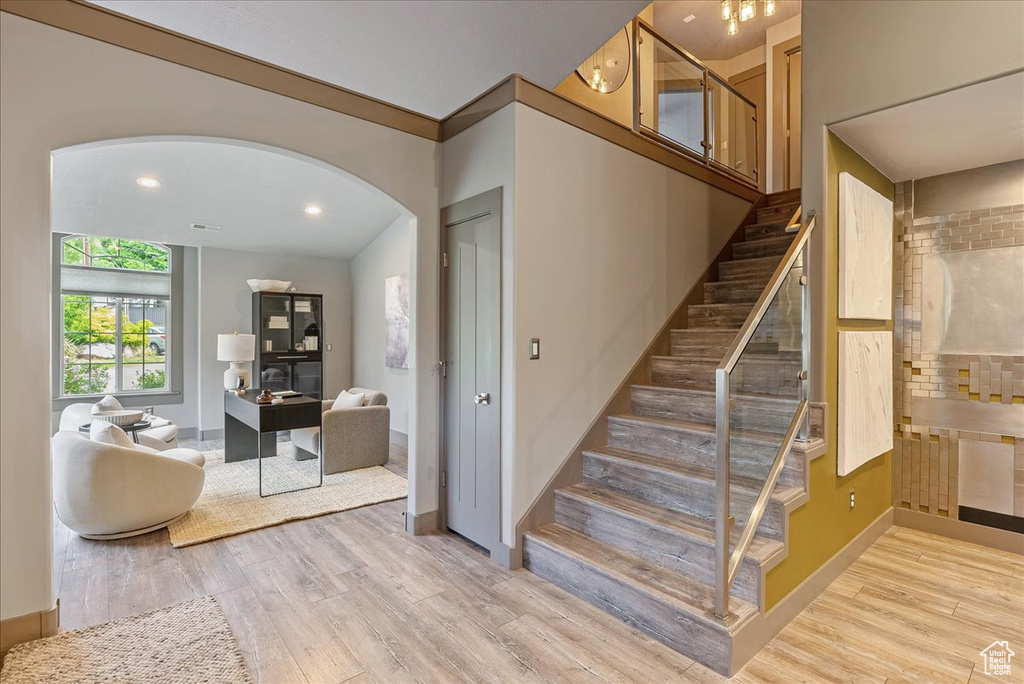 Staircase with arched walkways, wood finished floors, baseboards, and recessed lighting