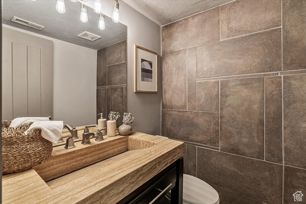 Bathroom featuring toilet, vanity, and a textured ceiling