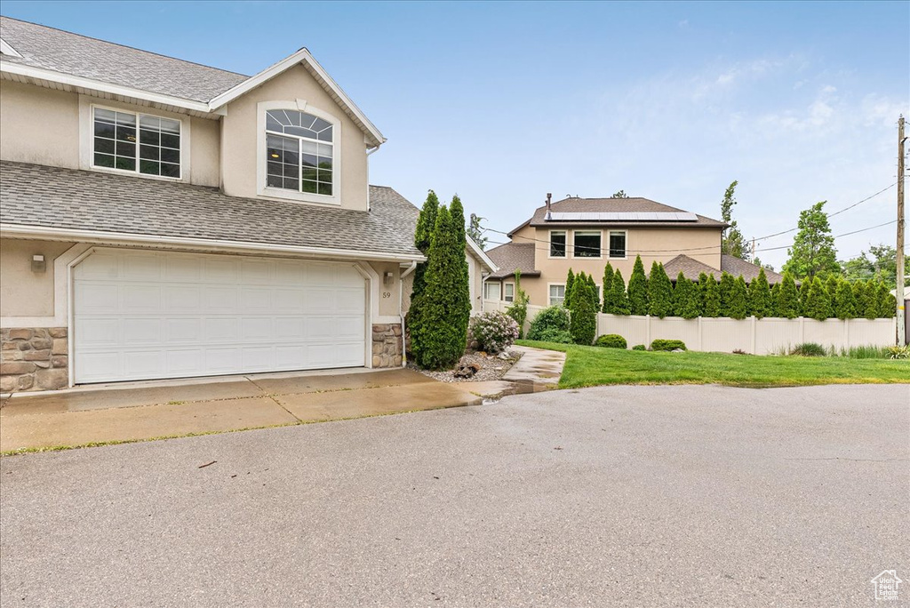 View of front of home with stone siding, stucco siding, an attached garage, and a shingled roof