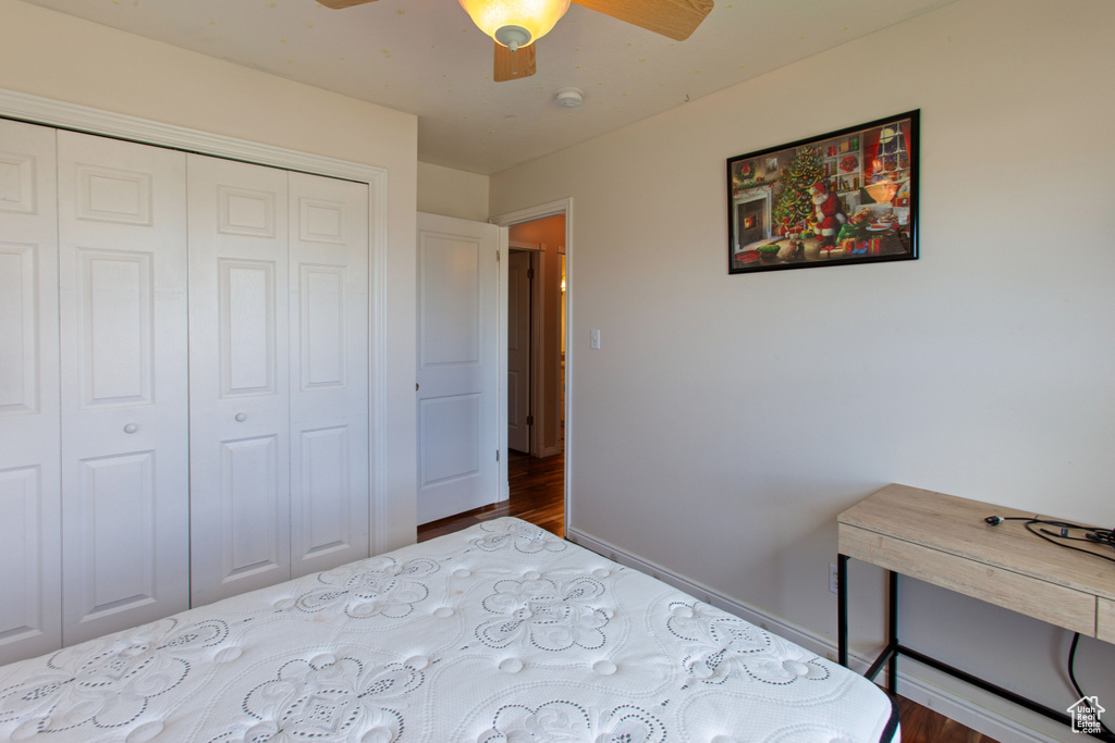 Bedroom with wood finished floors, a closet, ceiling fan, and baseboards