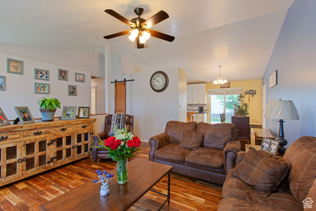 Living room featuring lofted ceiling, wood finished floors, a ceiling fan, and a barn door