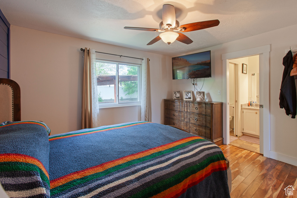 Bedroom featuring light wood-style floors, ensuite bath, ceiling fan, and baseboards