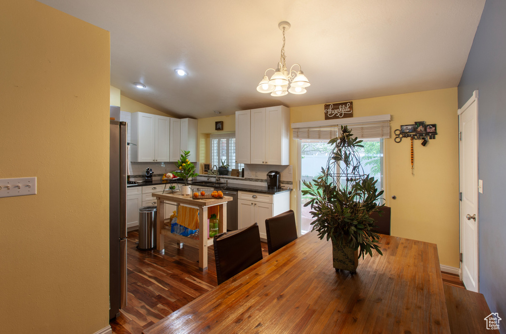 Dining room with a chandelier, lofted ceiling, dark wood-type flooring, and baseboards