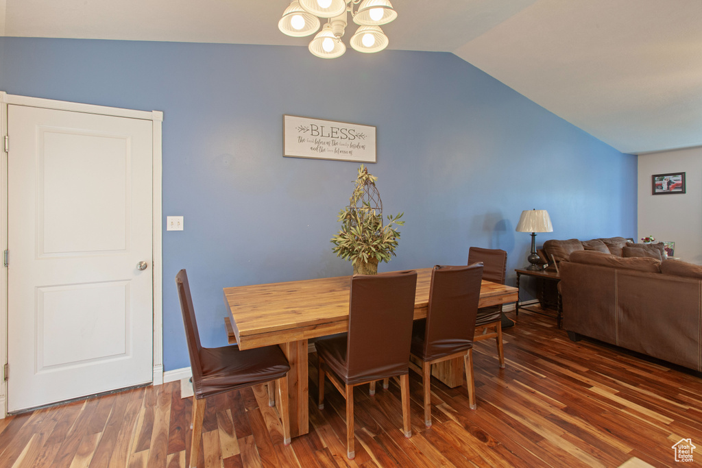 Dining space featuring lofted ceiling, wood finished floors, and a chandelier