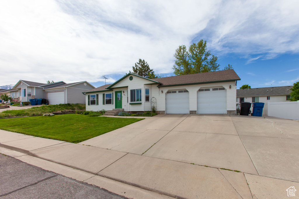 Ranch-style house with an attached garage, concrete driveway, and a front yard