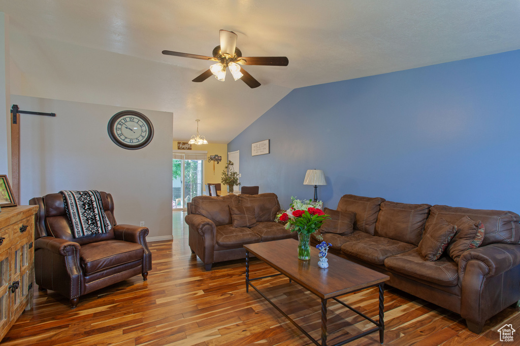 Living area featuring hardwood / wood-style floors, a ceiling fan, lofted ceiling, a barn door, and baseboards