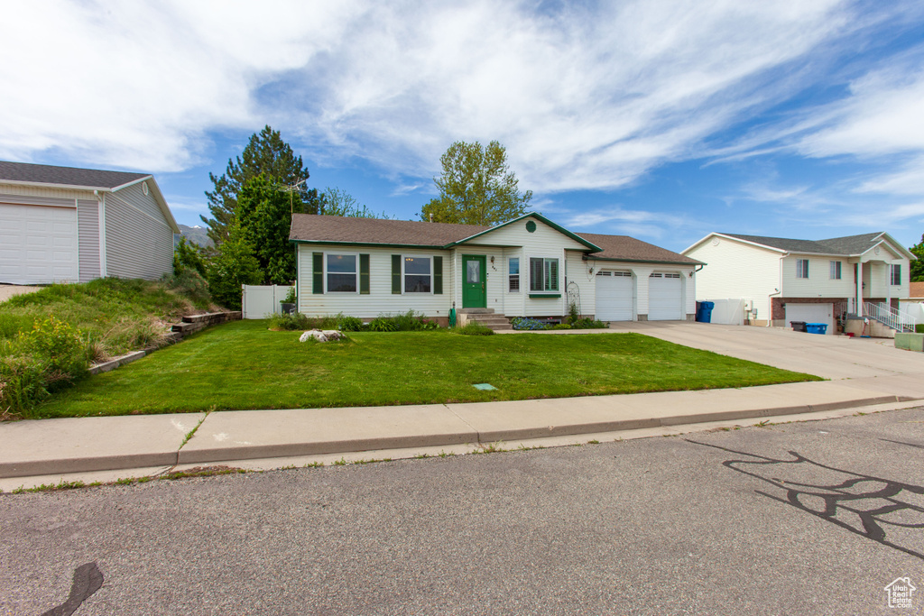 Ranch-style home with driveway, an attached garage, a front lawn, and entry steps