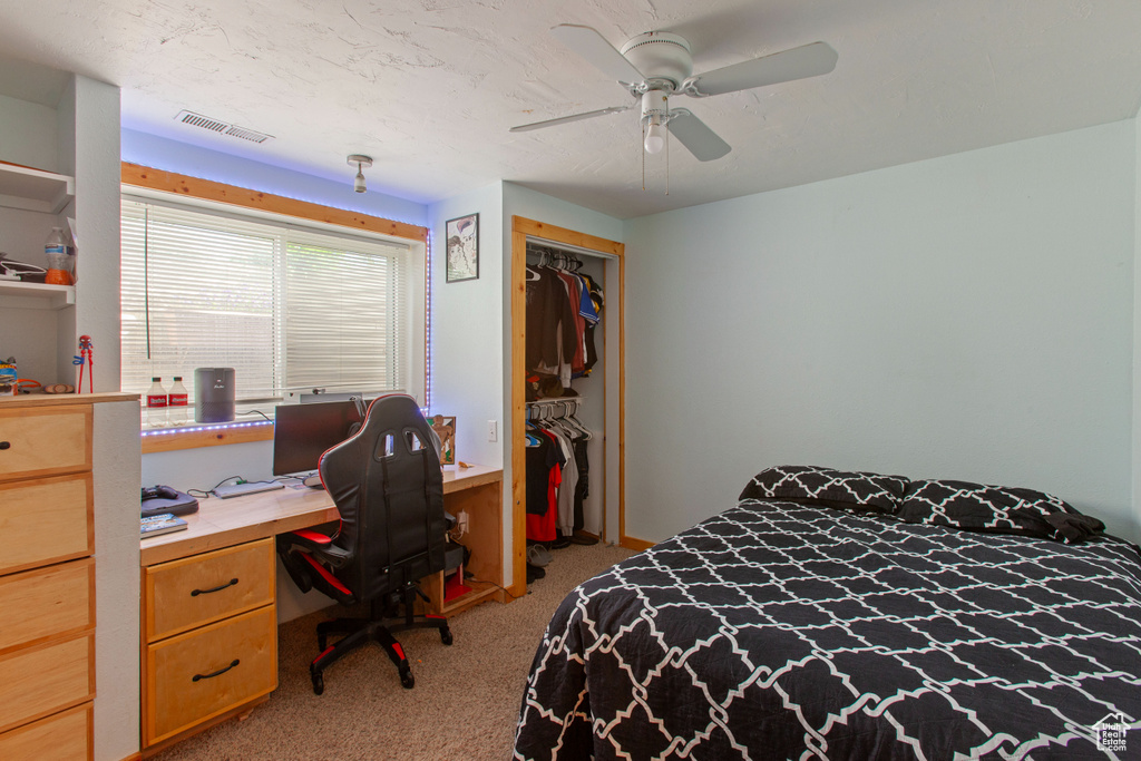 Bedroom with carpet floors, a closet, an office area, and a ceiling fan