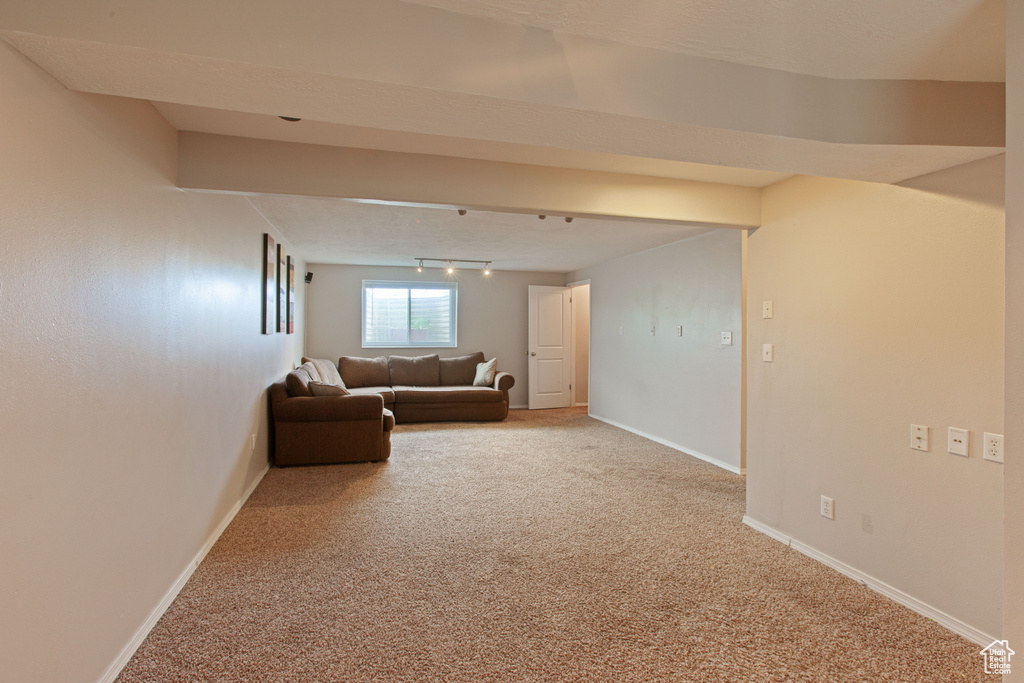 Carpeted living room featuring rail lighting and baseboards
