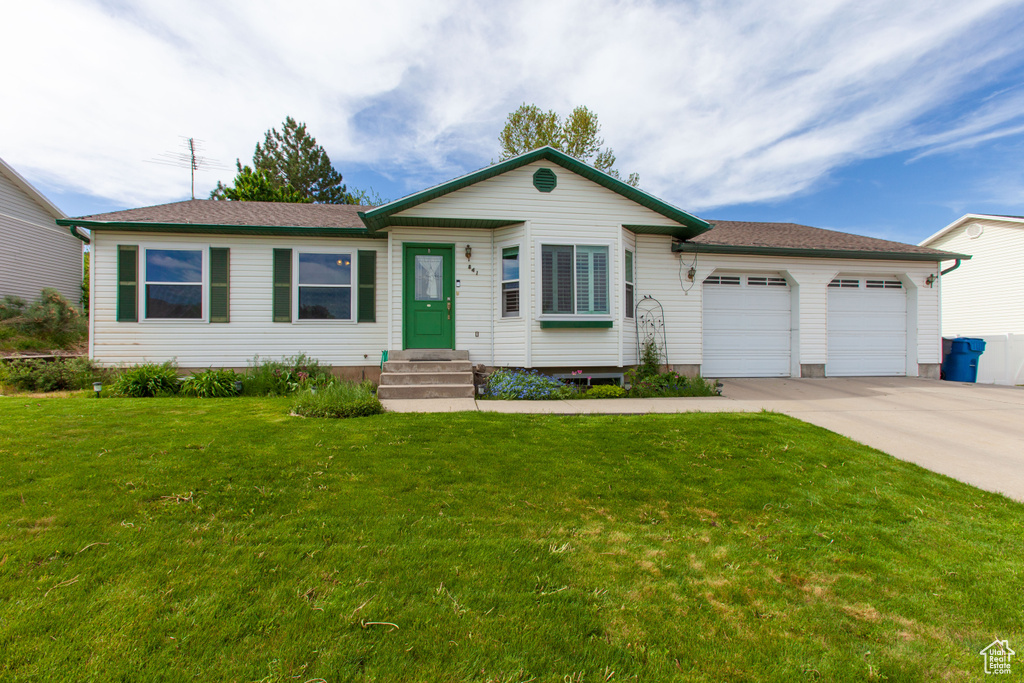 Ranch-style home with concrete driveway, an attached garage, and a front yard
