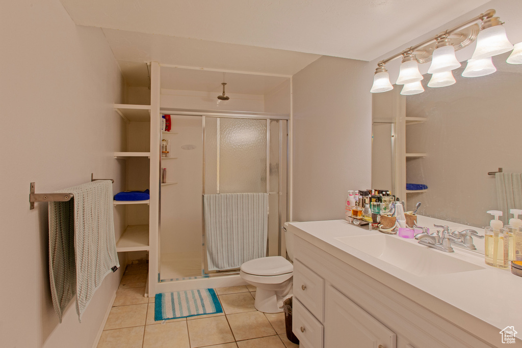 Bathroom with tile patterned floors, a shower stall, vanity, and toilet